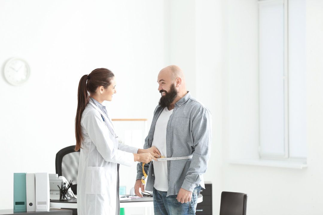 Doctor measuring a patient's waist during a medical weight loss consultation in a clinic.